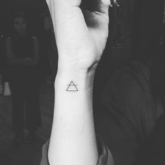 a woman's arm with a small triangle tattoo on the left side of her wrist