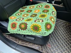 a green crocheted blanket sitting on the back of a car seat in a vehicle