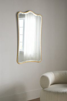 a white chair sitting in front of a mirror on the wall next to a window