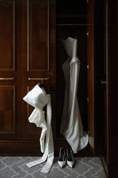 a wedding dress and shoes sit in the closet next to each other on a carpeted floor