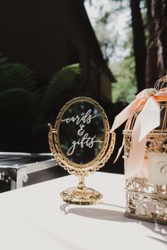 a small mirror sitting on top of a table next to a birdcage filled with flowers