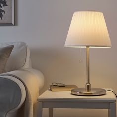 a table lamp sitting on top of a white end table next to a couch and chair