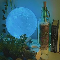 the moon lamp is next to some plants and candles on a table with books in front of it