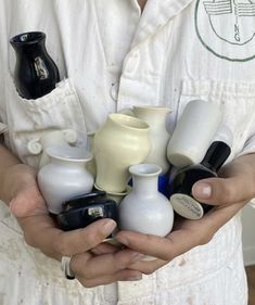 a person holding several different sized vases in their hands, all white and black