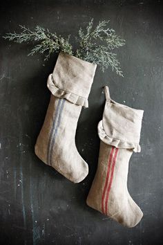 two christmas stockings hanging on a chalkboard with rosemary sprigs in the background