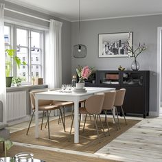 a dining room table with four chairs and a vase filled with flowers on top of it