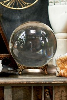 a glass ball sitting on top of a wooden table next to other vases and items