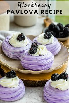 blackberry pavlovas with white frosting and blackberries are on a plate