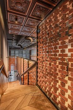 the interior of a building with red brick walls and wooden stairs leading up to an elevator