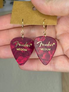 Introducing our stunning Simple Fender Guitar Pick Dangle Earrings - the perfect fusion of music and fashion! Crafted with genuine Fender guitar picks, these earrings exude an irresistible charm that resonates with music enthusiasts and style-conscious individuals alike. Each earring features a captivating Fender guitar pick, showcasing the iconic Fender logo or a unique and eye-catching design. The dangle style adds an elegant touch, allowing the guitar pick to sway gently, reflecting light and drawing attention to your ears with every movement. Fender Logo, Music And Fashion, Guitar Pick Earrings, Fender Guitar, Reflecting Light, Long Dangle Earrings, Guitar Picks, Huggie Hoop Earrings, Lightning Bolt