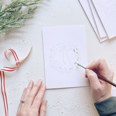 a person is drawing on paper with a brush