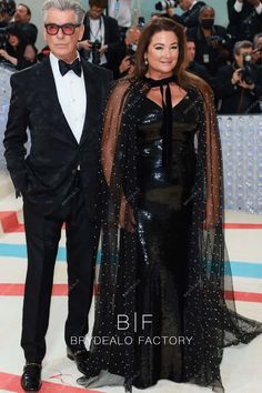 an older man and woman in formal wear standing next to each other on the red carpet