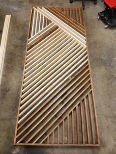 a wooden floor grate sitting on top of a cement floor next to a red chair