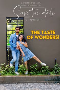 a man and woman standing next to each other in front of a sign that says save the date