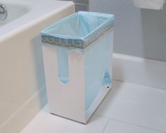 a blue trash can sitting next to a white bath tub in a bathroom with tile flooring