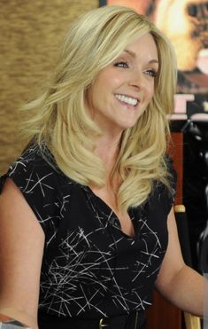 a woman sitting at a table with a glass of wine in her hand and smiling