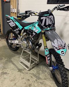 a dirt bike parked in a garage next to a wall with a sign on it