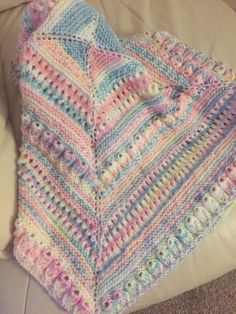 a crocheted blanket sitting on top of a couch