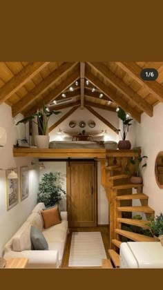 a living room filled with furniture next to a wooden stair case under a roof covered in lights