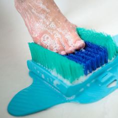 a person's hand on a blue and green brush