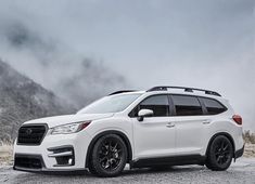 the white subarunt is parked in front of some mountains