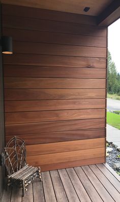 a bench sitting on top of a wooden deck next to a wall covered in wood planks