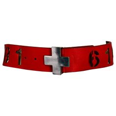 Norma Kamali Vintage Red Leather Novelty Cut Out Numbers Belt with Silver Cross Buckle S-M. Coral red leather belt with assorted cut out numbers, not sure if they mean anything, the numbers, that is. I've not seen another one, this from the 1990s. Attached silver metal cross buckle with a prong that works with the holes on the other end. Embossed stamp inside marked Norma Kamali S-M. In very good condition the cross buckle has a few light marks. Measurements are in inches: 32 1/2 from buckle hoo Embossed Stamp, Cross Buckle, Clawdeen Wolf, Vintage Givenchy, Wide Leather Belt, Metal Cross, Project Runway, Coral Red, Norma Kamali