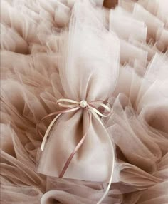 a white bag with a bow tied to it on top of some tulle fabric