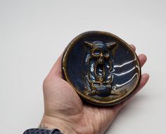 a hand holding a small ceramic object in it's palm