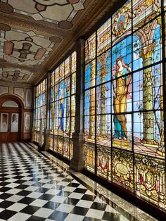 a long hallway with stained glass windows and checkered flooring on the side wall