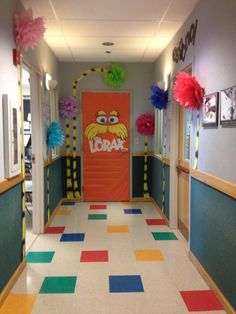 a hallway decorated with colorful paper pom poms and an orange door that says lorax