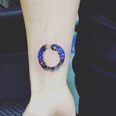 a woman's wrist with a tattoo on it that has a circular design in the middle