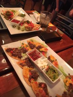 two plates filled with food on top of a wooden table next to another plate full of food