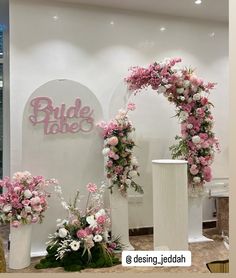 two white pillars with pink and white flowers on them in front of a sign that says bride takes