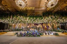 an elaborately decorated room with chandeliers and flowers on the ceiling, surrounded by greenery