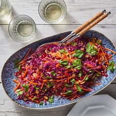 a bowl filled with coleslaw and carrots next to two glasses of water