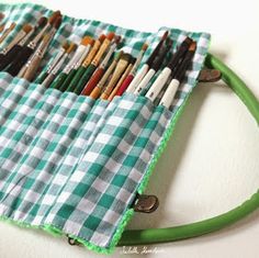 a green and white checkered bag with lots of paint brushes in it