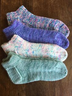 three pairs of socks sitting on top of a wooden floor next to each other in different colors