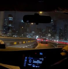 a car driving down a highway at night with city lights in the backgroud