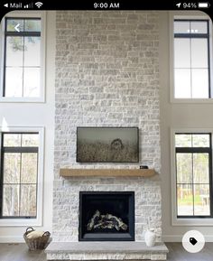 a living room filled with lots of windows and a fire place in the middle of it