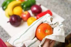 a person holding a cloth over a pile of fruits and vegetables