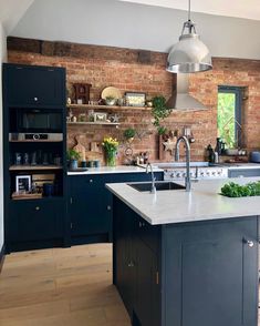 a kitchen with blue cabinets and white counter tops, an island sink and brick wall