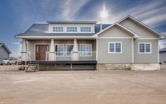 a large gray house sitting on top of a dirt field