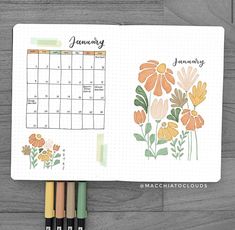 a planner with flowers on it next to markers and pencils in front of the calendar