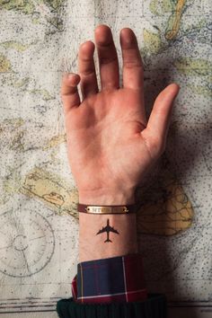 a person's hand with a plane tattoo on it, and a world map in the background