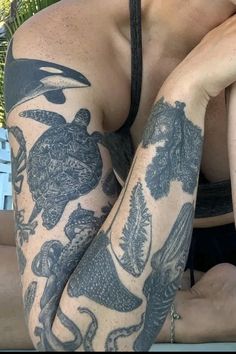 a woman with tattoos on her arm and chest sitting in front of a pool side chair