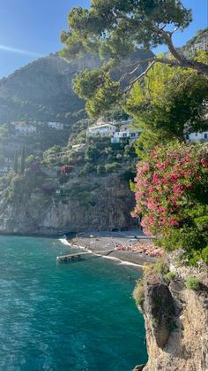 the beach is surrounded by trees and houses on the cliff above water's edge