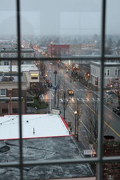 the view from an apartment window looking down at a city street and snow covered ground