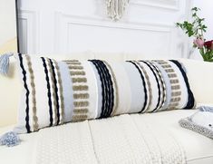 a white couch with striped pillows on it and a plant in the corner next to it