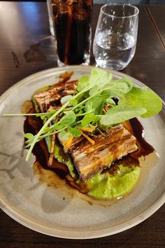 a white plate topped with meat and veggies on top of a wooden table